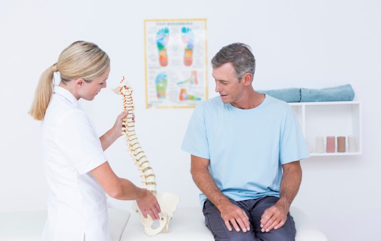 Chiropractor explaining a spine model to a patient